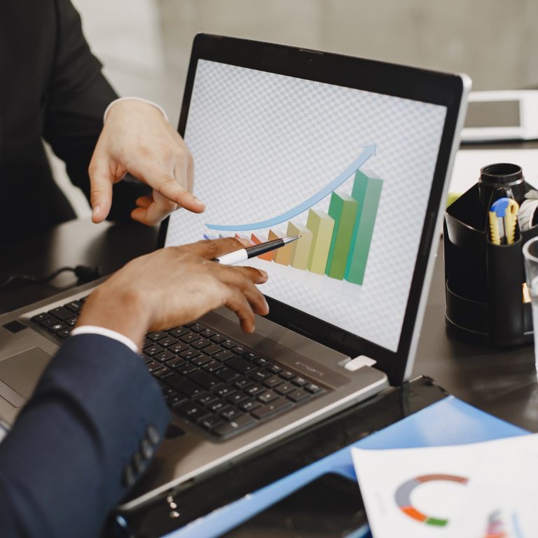 Supertech Computer partners discussing IT solutions in the office, African businessman in a black suit working with laptop.